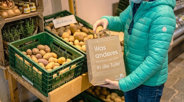 Verpacken von Kartoffeln in eine Papiertragetasche Eine Papiertragetasche wird von einer Kundin mit Kartoffeln gefüllt